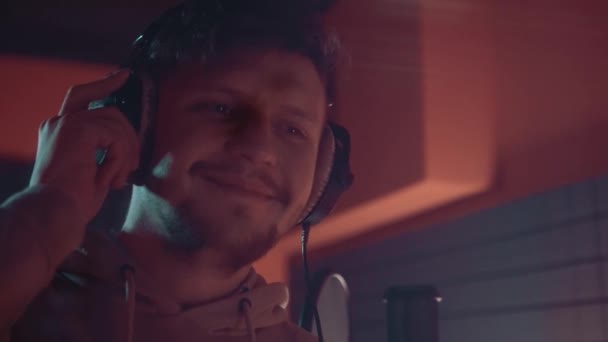 Cantante en el estudio escuchando música en auriculares y sonriendo — Vídeos de Stock