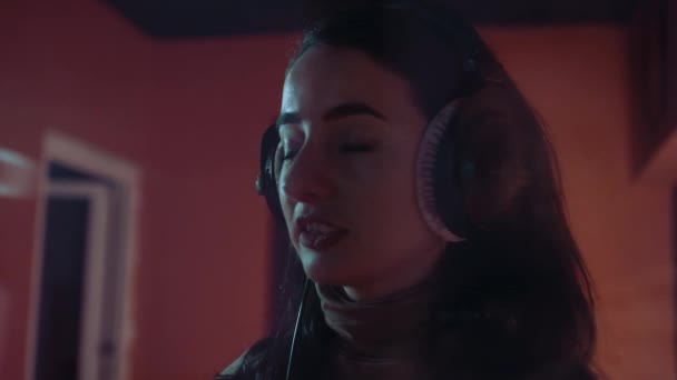 La cantante sonríe y escucha música en auriculares en el estudio — Vídeo de stock