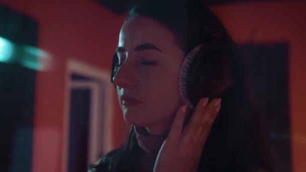 La cantante sonríe y escucha música en auriculares en el estudio — Vídeo de stock