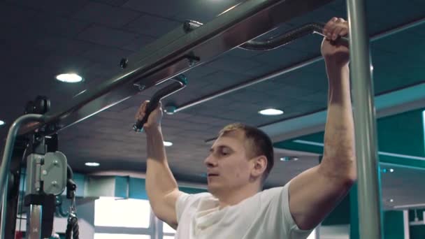 Der junge Kerl ist in einem Fitnessraum beschäftigt — Stockvideo