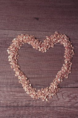 kırmızı bir renk tonu ile ahşap bir tabloda yulaf ezmesi ile kaplı kalp