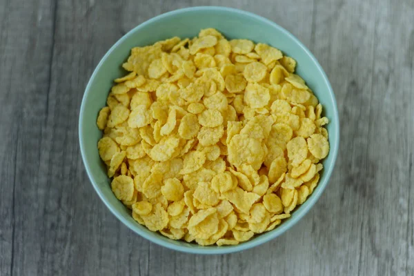 Corn flakes are poured into a green plate — Stock Photo, Image