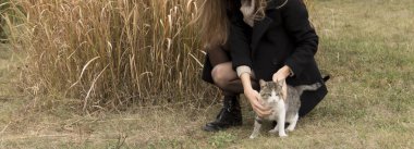 Kız bir siyah ceket ve a kedi karşı okşayarak bej kazak 