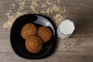 siyah bir plaka üzerinde üç yulaf ezmeli kurabiye yalan, yulaf ezmesi dağınık