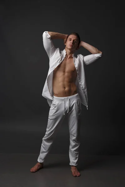 Chlap s nahou trupu, v bílých kalhotách a bílé košili, stojí na šedém pozadí — Stock fotografie