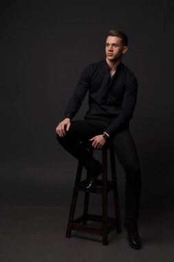 gri bir arka plan üzerinde çıplak bir gövde, beyaz pantolon ve beyaz gömlek, bir adamla standları