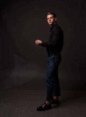 karanlık bir arka plan üzerinde siyah gömlek ve Mavi pantolon çekici beyaz adam standları