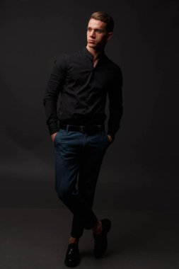 karanlık bir arka plan üzerinde siyah gömlek ve Mavi pantolon çekici beyaz adam standları