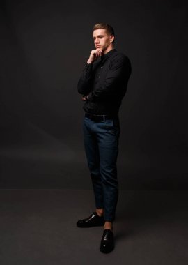 karanlık bir arka plan üzerinde siyah gömlek ve Mavi pantolon çekici beyaz adam standları