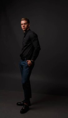 karanlık bir arka plan üzerinde siyah gömlek ve Mavi pantolon çekici beyaz adam standları