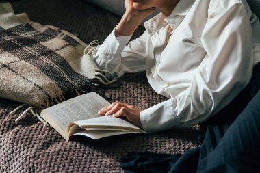 kız sıcak bir battaniye bir kitap okuma. kadın yatıyor, yatak, bir battaniye, bir kanepe, bir kanepe uzandı ve tutan bir kitap. Kız bir kitap okuma