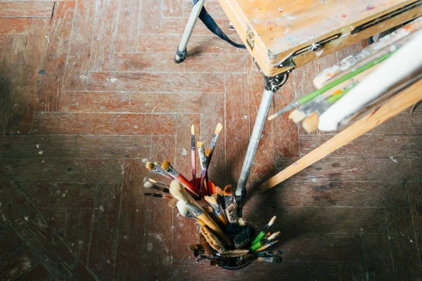 Cepillos para dibujar en un caballete de madera viejo, de pie en el suelo — Foto de Stock