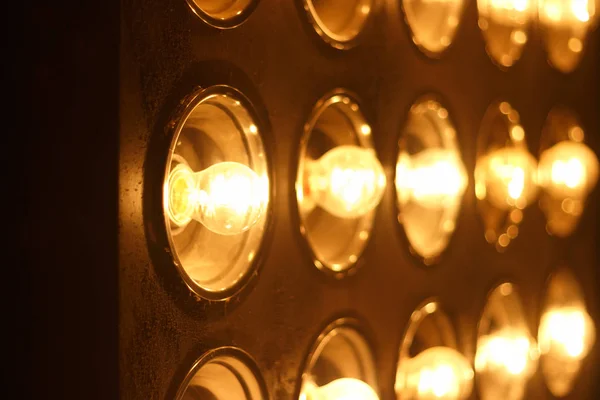 Light bulbs background over dark wall, blur — Stock Photo, Image