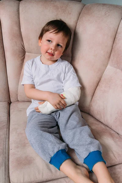 Egy kisfiú ül egy széken, egy törött kar, a leadott. Kórház. gyógyszer. veszély. a fájdalom. megtörni a végtagok. erőszak. — Stock Fotó