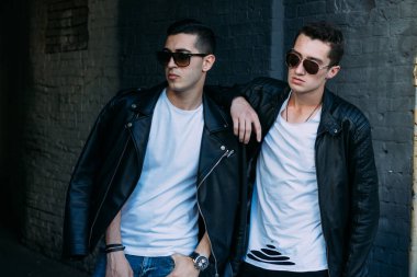 Güzel ve çekici bir adam şehirde poz veriyor. Siyah gözlüklerle şehirde dolaş. İletişim. arkadaşlarla buluş.