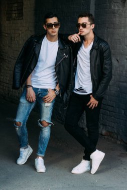 Güzel ve çekici bir adam şehirde poz veriyor. Siyah gözlüklerle şehirde dolaş. İletişim. arkadaşlarla buluş.