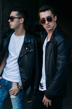 Güzel ve çekici bir adam şehirde poz veriyor. Siyah gözlüklerle şehirde dolaş. İletişim. arkadaşlarla buluş.