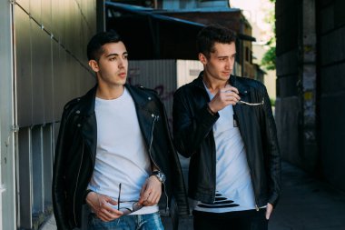 Güzel ve çekici bir adam şehirde poz veriyor. Siyah gözlüklerle şehirde dolaş. İletişim. arkadaşlarla buluş.