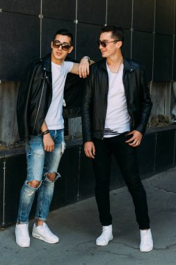 Güzel ve çekici bir adam şehirde poz veriyor. Siyah gözlüklerle şehirde dolaş. İletişim. arkadaşlarla buluş.