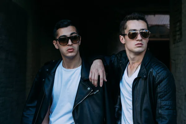 Chico hermoso y atractivo está de pie en la ciudad, posando. caminar por la ciudad en gafas negras. comunicación. reunión con amigos . — Foto de Stock