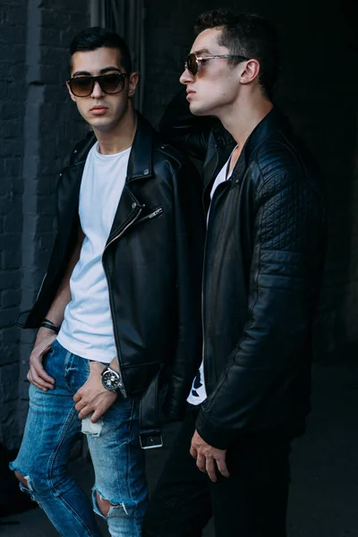 Güzel ve çekici bir adam şehirde poz veriyor. Siyah gözlüklerle şehirde dolaş. İletişim. arkadaşlarla buluş.