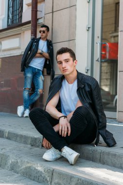 Güzel ve çekici bir adam şehirde poz veriyor. Siyah gözlüklerle şehirde dolaş. İletişim. arkadaşlarla buluş.