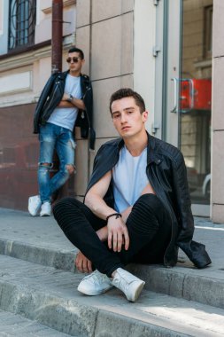 Güzel ve çekici bir adam şehirde poz veriyor. Siyah gözlüklerle şehirde dolaş. İletişim. arkadaşlarla buluş.