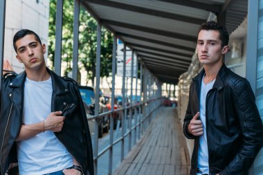 Güzel ve çekici bir adam şehirde poz veriyor. Siyah gözlüklerle şehirde dolaş. İletişim. arkadaşlarla buluş.