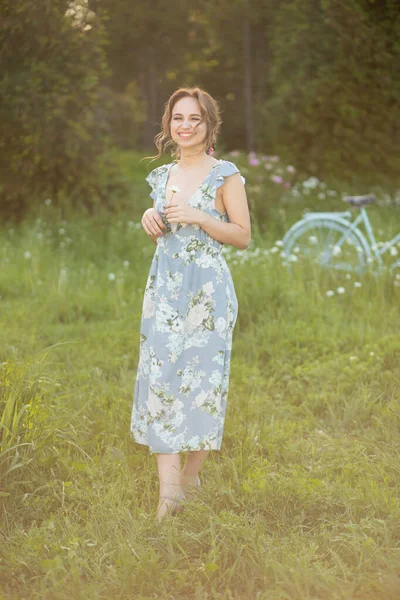 Belle fille au coucher du soleil en été dans un champ avec une fleur à la main, marche en été, va, le soleil brille — Photo