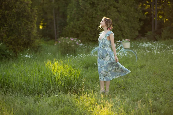Piękna dziewczyna o zachodzie słońca w lecie na polu z kwiatem w ręku, spacery w lecie, idzie, słońce świeci — Zdjęcie stockowe