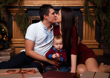 Hediye kutuları olan aile Noel ağacının yanında oturur, gülüp oynarlar, aile mutluluğu, şömine, kalplerin sıcaklığı.