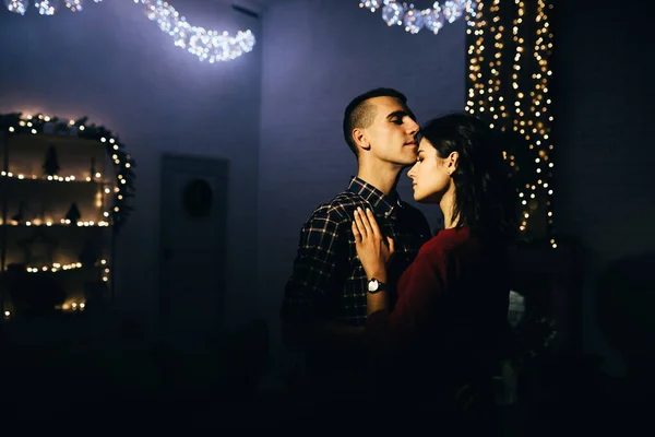 Mutlu, karanlıkta aşık bir çift, kanepede bir akşam, karanlık bir arka plan, Noel ağacı ışıkları. Noel akşamı. Yeni yıl. Sarıl ve öp. Çekicilik, romantik akşam ve randevu. — Stok fotoğraf
