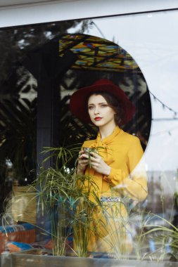 Kafede bir fincan kahve ve şapkalı bir kız. Sarkık şapkalı ve fiyonklu bluz giyen şehvetli bir genç kızın portresi. Kafede elinde kahve tutan güzel esmer kadın.