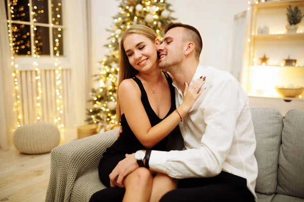 Casal no amor beijos e abraços no sofá perto das luzes da árvore de Natal. Noite de Ano Novo. Natal. . — Fotografia de Stock