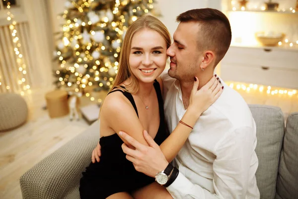 Пара закоханих поцілунків і обіймів на дивані біля ялинкових вогнів. Новорічна ніч. Різдво . — стокове фото