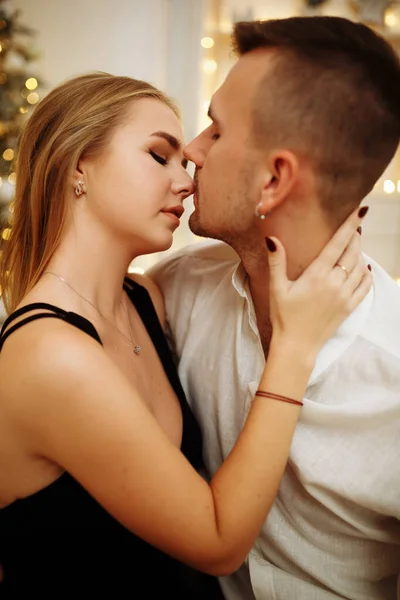 Casal no amor beijos e abraços no sofá perto das luzes da árvore de Natal. Noite de Ano Novo. Natal. . — Fotografia de Stock