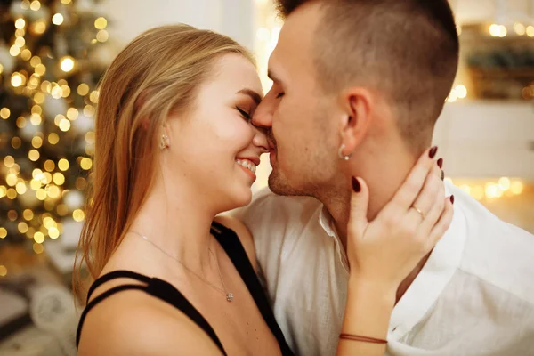 Couple en amour baisers et câlins sur le canapé près des lumières du sapin de Noël. La nuit du Nouvel An. Noël . — Photo