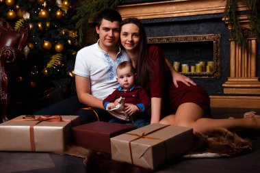 Hediye kutuları olan aile Noel ağacının yanında oturur, gülüp oynarlar, aile mutluluğu, şömine, kalplerin sıcaklığı.