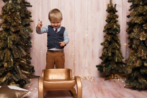Noel ağaçlarının yanında kızağın üzerinde bir oğlan, Noel ışıkları, neşe ve gülümsemeler, oyunlar. tatil ve tatil — Stok fotoğraf