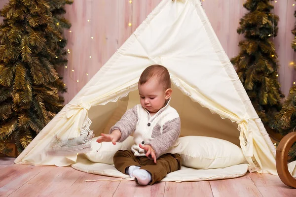 Um menino perto da tenda, tipi, wigma e árvores de natal, está brincando . — Fotografia de Stock