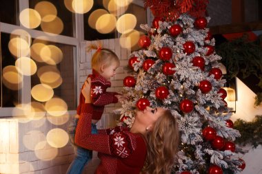 Gülümseyen anne kızıyla birlikte Noel ağacının yanında