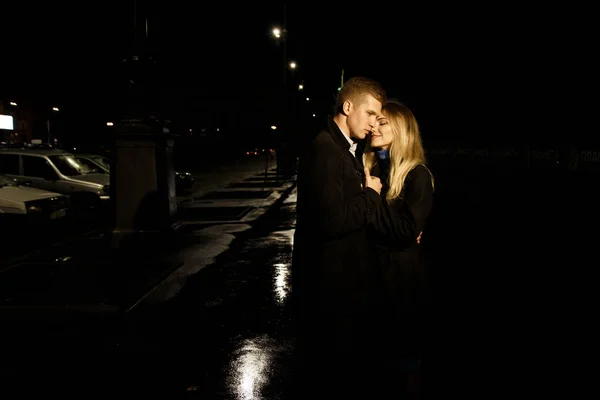 Para zakochana obejmująca ciemne tło, noc, deszcz, budynki w mieście, park, uśmiechnięta, przyciągająca. Facet przytula dziewczynę. Walentynki — Zdjęcie stockowe