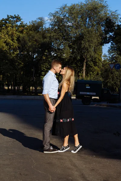Casal feliz abraçando e de pé em frente à cidade. fundo escuro, o sol brilha sobre os amantes — Fotografia de Stock
