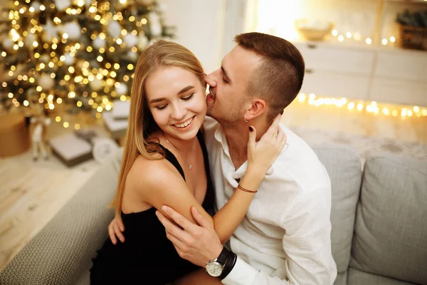 Пара закоханих поцілунків і обіймів на дивані біля ялинкових вогнів. Новорічна ніч. Різдво . — стокове фото