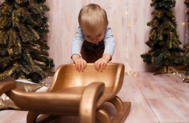 Noel ağaçlarının yanında kızağın üzerinde bir oğlan, Noel ışıkları, neşe ve gülümsemeler, oyunlar. tatil ve tatil
