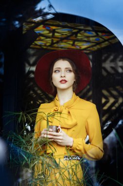 Kafede bir fincan kahve ve şapkalı bir kız. Sarkık şapkalı ve fiyonklu bluz giyen şehvetli bir genç kızın portresi. Kafede elinde kahve tutan güzel esmer kadın.