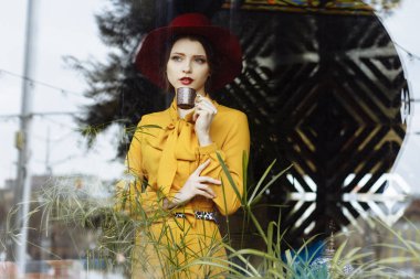 Kafede bir fincan kahve ve şapkalı bir kız. Sarkık şapkalı ve fiyonklu bluz giyen şehvetli bir genç kızın portresi. Kafede elinde kahve tutan güzel esmer kadın.