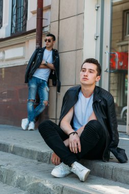 Güzel ve çekici bir adam şehirde poz veriyor. Siyah gözlüklerle şehirde dolaş. İletişim. arkadaşlarla buluş.