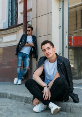 Güzel ve çekici bir adam şehirde poz veriyor. Siyah gözlüklerle şehirde dolaş. İletişim. arkadaşlarla buluş.