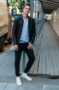 Çekici ve yakışıklı adam girişte duruyor ve beyaz tişört ve siyah deri ceketlerle gülüyor. iletişim.